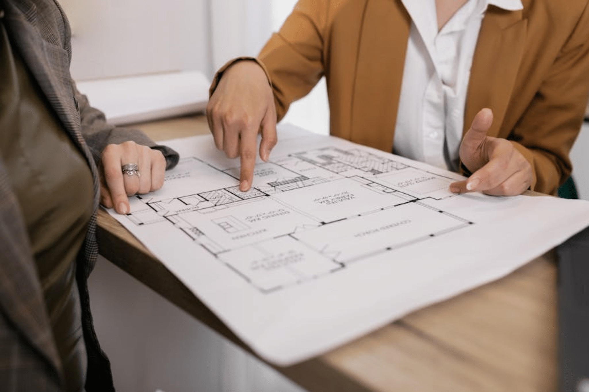 Two people reviewing a building floorplan document.