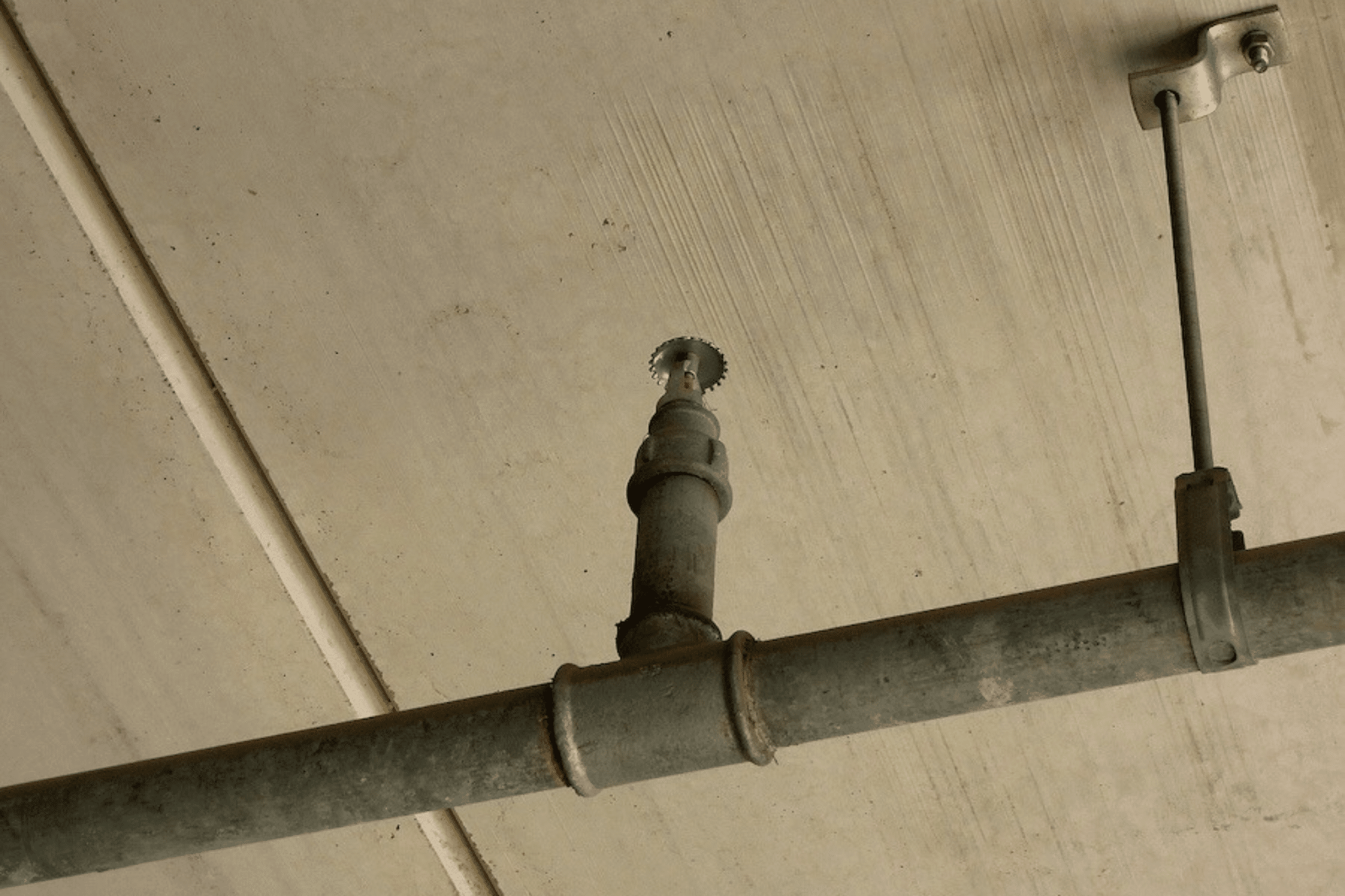 What You Think You Know About Fire Sprinklers (and What’s Actually True) Misinformation about fire sprinklers is everywhere: TV shows, movies, even word of mouth. Statements like “fire sprinklers do more damage than fire” are repeated so often that some people start to believe it’s true. For facilities teams, this confusion can lead to hesitation, deferred upgrades, or missed maintenance that puts people and property at serious risk. Here’s a clear, practical look at how sprinkler systems actually work and what that means for your building’s fire life safety strategy. Myth #1: “All the sprinklers go off at once.” False! In the vast majority of facilities (offices, retail, multifamily, and education), sprinkler heads activate individually based on heat at that specific location. That’s how a single head can stop a small fire from becoming a big one. In fact, in most building fires, one or two sprinkler heads are enough to control or extinguish the incident before it grows. There are specialty “deluge” systems where all nozzles release water together, but those are designed for specific high-hazard industrial environments. Common sprinkler system types: Wet systems (most common in conditioned spaces): Piping is filled with water and a head opens only where heat is present. Dry systems (common in parking garages, freezers): Piping is filled with pressurized air; when a head opens, air releases and a valve admits water. This way, water won’t freeze in pipes in outdoor or exposed areas. Pre-action systems (data centers, museums): Require a detection event plus head activation to release water. Adds extra protection against accidental discharge. Accidental activations are rare and typically the result of physical damage (e.g., a forklift striking a head), not spontaneous operation. Myth #2: “Smoke sets off sprinklers.” Not true. Sprinklers respond to heat, not smoke. A heat-sensitive element (typically set around 155°F and 200°F or higher in some manufacturing settings) releases at a precise temperature. Detection devices may trigger alarms based on smoke, but they don’t open sprinkler heads in standard systems. Myth #3: “All sprinkler systems are the same.” False. Fire sprinkler systems are tailored to specific hazards, ceiling heights, water supply, ambient temperatures, and code requirements. From pipe schedule vs. hydraulically calculated systems to commodity classifications in storage, a well-designed system is purpose-built, not one-size-fits-all. Myth #4: “Once installed, sprinklers don’t need maintenance.” Not true. Ongoing inspection, testing, and maintenance is essential. Unmonitored or closed control valves, impaired water supplies, or missed inspections are common reasons fires get out of hand. We’ve seen buildings suffer major losses because valves were shut and not supervised. Sprinklers are reliable, but neglected systems are not. Myth #5: “Older sprinkler systems don’t need upgrades.” Untrue. Codes evolve with new materials, construction methods, and risks. Many legacy systems are undersized by today’s standards or use components that are no longer compliant. In older systems, pipe corrosion poses a real risk of leaks and faulty systems. Proactive upgrades can prevent costly last-minute replacements, support insurance requirements, and keep transactions moving when properties change hands. We’ve seen property sales fall through because fire sprinkler systems were outdated—don’t let that happen to your facility! Myth #6: “Sprinklers cause more damage than fire.” We hear this one a lot, but it’s simply untrue. Water damage from one or two operating heads is far less destructive than uncontrolled fire and smoke. Time and again, single-head activations in offices, corridors, and retail spaces have contained incidents to the area of origin, keeping occupants safe and businesses open. Myth #7: “Sprinkler systems are too expensive.” Reality: The cost of a system is modest compared to property loss, liability, and business interruption. Many owners also realize insurance benefits and improved asset value. Preventing a single serious fire can more than offset the investment. Myth #8: “Sprinklers will ruin the aesthetic.” False. Today’s options blend in with architecture. Concealed and flush heads, round or square cover plates, and factory-painted finishes can color-match your interiors. Specialty heads (e.g., stainless steel in food-grade or clean environments) meet hygiene and durability needs. But a quick note: never DIY field-paint sprinkler heads or plates—this compromises performance and compliance! Let us know if you want to customize your system, and we’ll do it according to code. Need Sprinkler System Maintenance or Installation? Sciens installs, inspects, and services fire sprinkler systems across hospitality, healthcare, education, MDUs, and complex capital projects. We custom-design systems to your specific setting, whether that’s EV-ready parking structures or technology spaces where water release must be tightly controlled. Ready to separate myth from reality in your building? Let’s evaluate your current protection, identify gaps, and tailor a code-compliant, future-ready sprinkler solution for your facility. Contact Sciens to find a local provider and get started today.